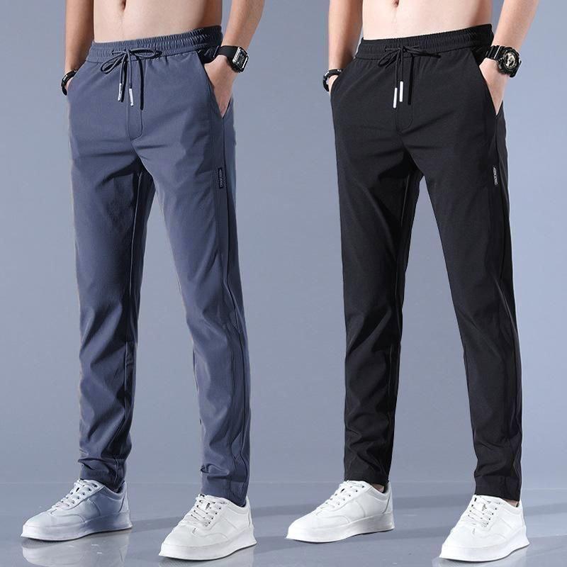 Two pairs of men's jogger pants in gray and black on a gray background.